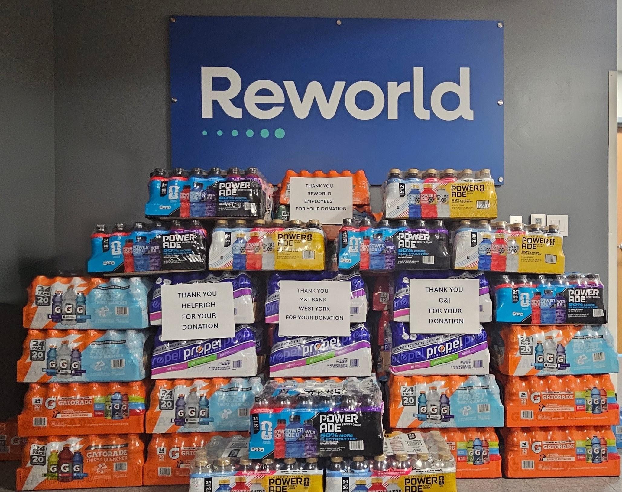 Reworld Waste team members delivering cases of donated sports drinks to soup kitchen volunteers