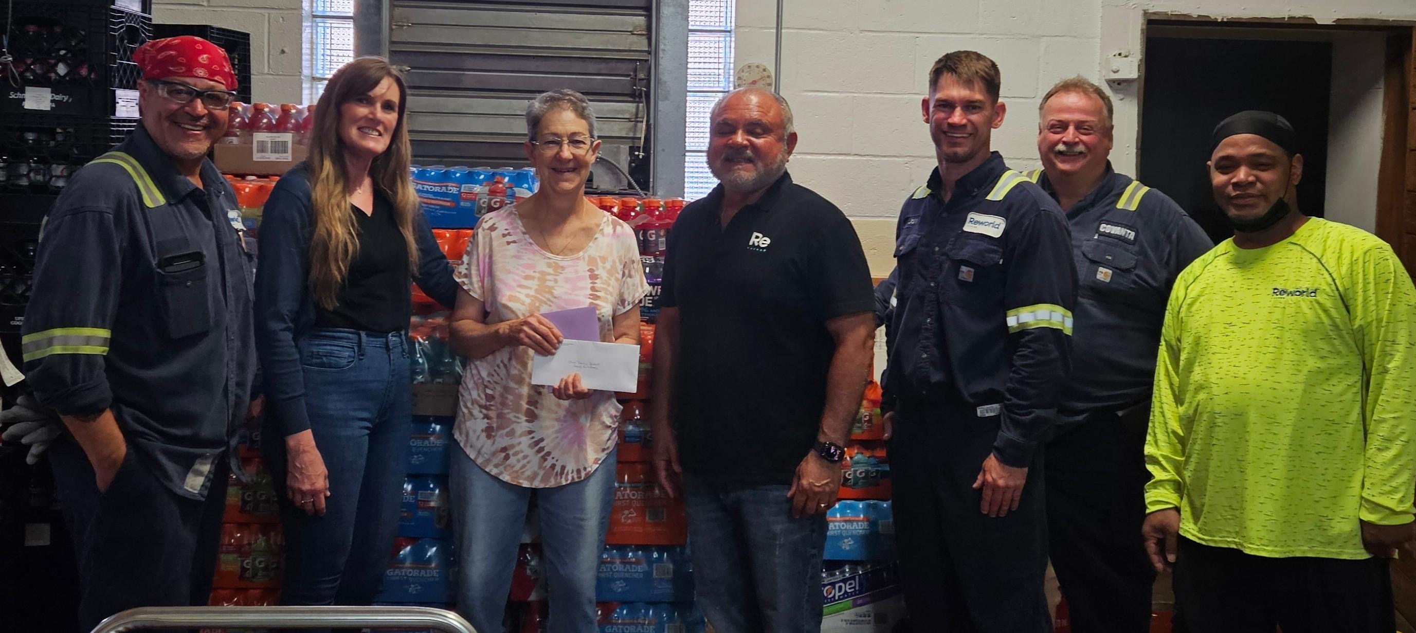Volunteers at Our Daily Bread standing beside donated beverage cases with appreciation